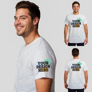 May include: White t-shirt with the text "YOUR DESIGN HERE" on the front, back, and sleeve. The text is in a black, yellow, and blue design. The t-shirt is being worn by a person.