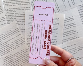 May include: A pink and white bookmark with the text "Romance Lovers Book Club" and "Admit One". The bookmark is decorated with hearts and a white border. The text "Never not thinking of you - Virginia Woolf" is written in a smaller font at the bottom of the bookmark.
