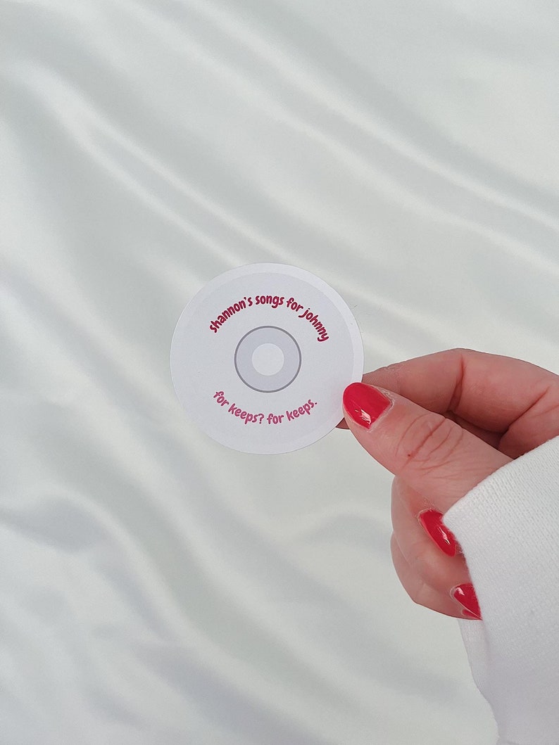 May include: White circular sticker with pink text that reads "Shannon's songs for Johnny for keeps? for keeps."