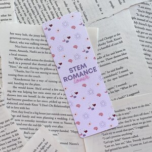 Op de afbeelding: Een paarse en roze bladwijzer met een patroon van hersenen en harten. De bladwijzer heeft de tekst "STEM Romance" in wit met een roze omtrek.