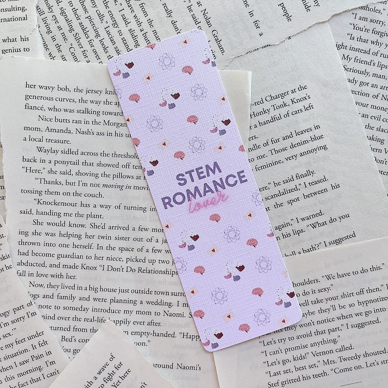 Op de afbeelding: Een paarse en roze bladwijzer met een patroon van hersenen en harten. De bladwijzer heeft de tekst "STEM Romance" in wit met een roze omtrek.