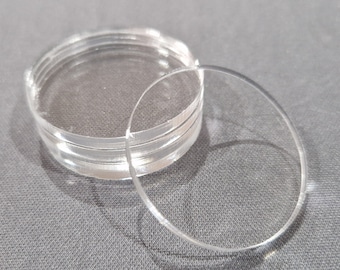 May include: A stack of clear acrylic round discs, with one disc laying on top of the stack.