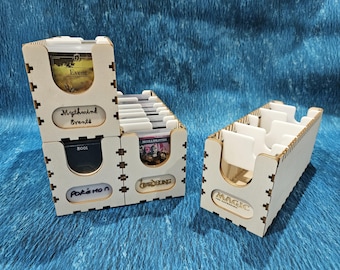 May include: Wooden card organizers with laser-cut designs. One organizer is labeled "Mythwind Events" and "Pokémon", while another is labeled "Magic: The Gathering". The organizers are designed to hold trading cards.