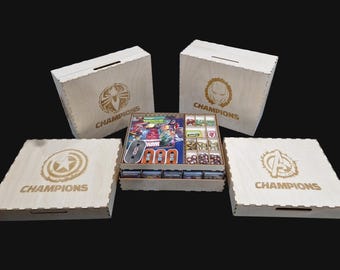 May include: Wooden game organizer for Marvel Champions. Includes four boxes with superhero logos and the word "Champions". The central organizer holds game components, cards, and tokens. The logos include Spider-Man, Iron Man, Captain America, and the Avengers.