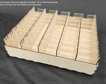 May include: A wooden card storage box with clear dividers. The box is rectangular with multiple compartments for organizing cards. The text on the image says, "Card storage is the same regardless of height. Up to 1500 sleeved cards."