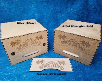 May include: Three wooden boxes with the words "Spirit Island" engraved on the top. The boxes are shown in three different finishes: oiled clear, oiled Georgian oak, and sanded untreated.