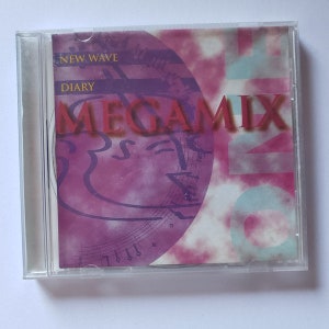 May include: A CD case with a pink and blue design. The title of the CD is "New Wave Diary Megamix".