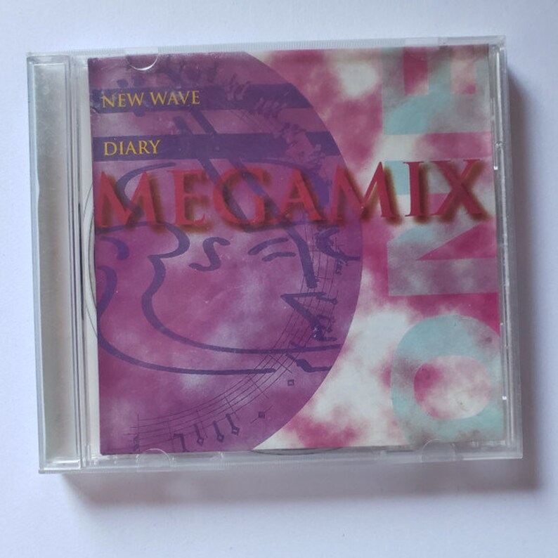 May include: A CD case with a pink and blue design. The title of the CD is "New Wave Diary Megamix".