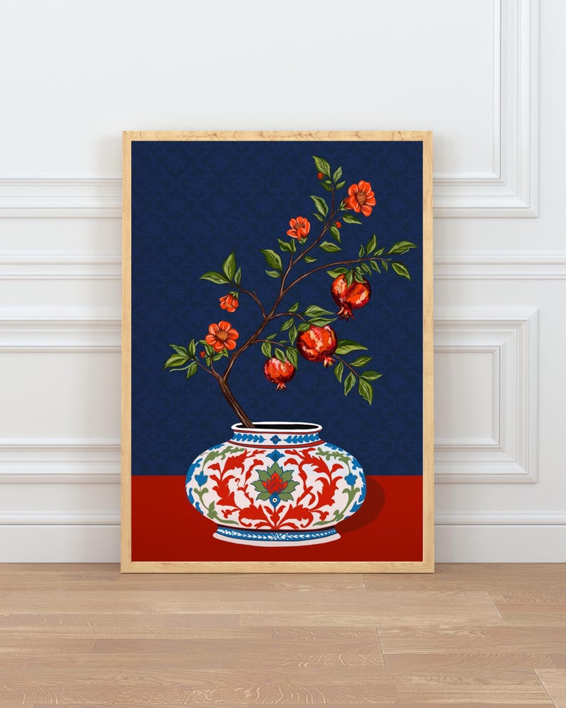 May include: A framed wall art print featuring a decorative ceramic vase with a white, red, and blue floral pattern. A branch with green leaves, orange blossoms, and red pomegranate fruits emerges from the vase against a dark blue background.