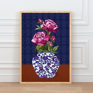 May include: A framed wall art print featuring a white ceramic vase with blue and orange floral patterns, holding a bouquet of vibrant pink peony flowers and green leaves, set against a dark blue background with a subtle repeating floral motif.
