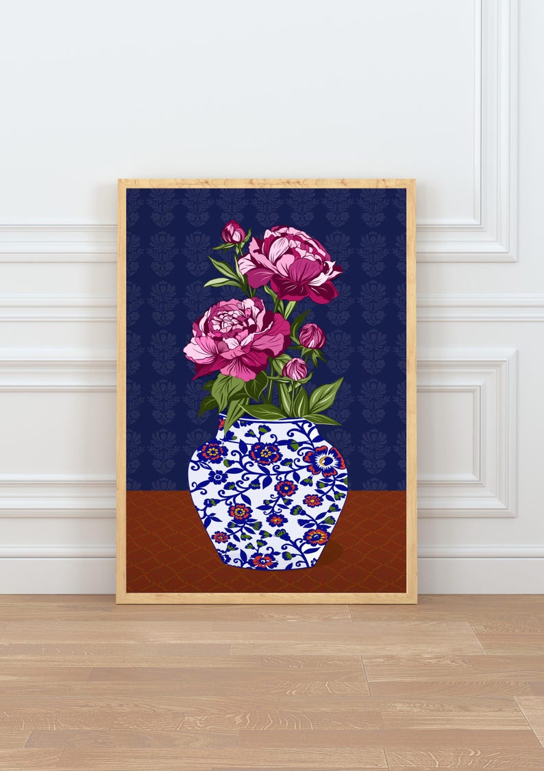May include: A framed wall art print featuring a white ceramic vase with blue and orange floral patterns, holding a bouquet of vibrant pink peony flowers and green leaves, set against a dark blue background with a subtle repeating floral motif.