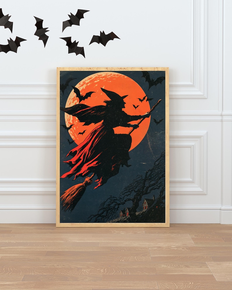 K&ouml;nnte beinhalten: Ein gerahmter, rechteckiger Wandkunstdruck mit der Silhouette einer Hexe auf einem Besenstiel vor einem gro&szlig;en, orangefarbenen Vollmond. Der dunkelblaue Nachthimmel zeigt mehrere fliegende Flederm&auml;use und die Silhouette eines Hauses.