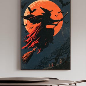K&ouml;nnte beinhalten: Ein rechteckiger Wandkunstdruck mit der schwarzen Silhouette einer Hexe, die auf einem Besen vor einem gro&szlig;en, leuchtend orangefarbenen Vollmond fliegt. Der dunkle Nachthimmel ist voller Flederm&auml;use und ein kleines, dunkles Haus steht unten.