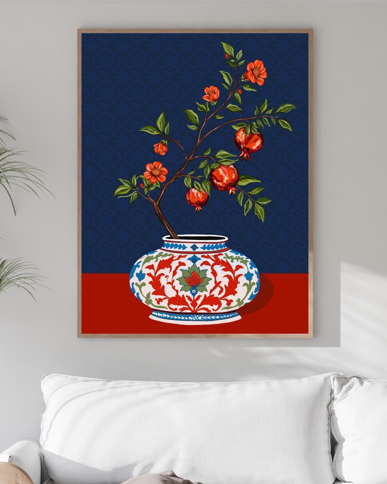 May include: A framed wall art print featuring a pomegranate branch with orange-red flowers and ripe red fruits emerging from a white, red, and blue patterned ceramic vase. The background is a deep navy blue with a subtle repeating floral pattern.