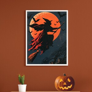 K&ouml;nnte beinhalten: Ein gerahmter Wandkunstdruck mit der Silhouette einer Hexe, die auf einem Besenstiel vor einem gro&szlig;en, leuchtend orangefarbenen Vollmond fliegt. Der dunkelblaue Nachthimmel ist voller fliegender Flederm&auml;use und ein dunkler, blattloser Baum steht &uuml;ber einem kleinen Haus.