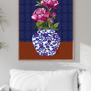 May include: A framed wall art print featuring a white ceramic vase with blue and orange floral patterns. The vase holds several vibrant magenta peony flowers and green leaves. The background is a deep navy blue with a subtle repeating pattern.