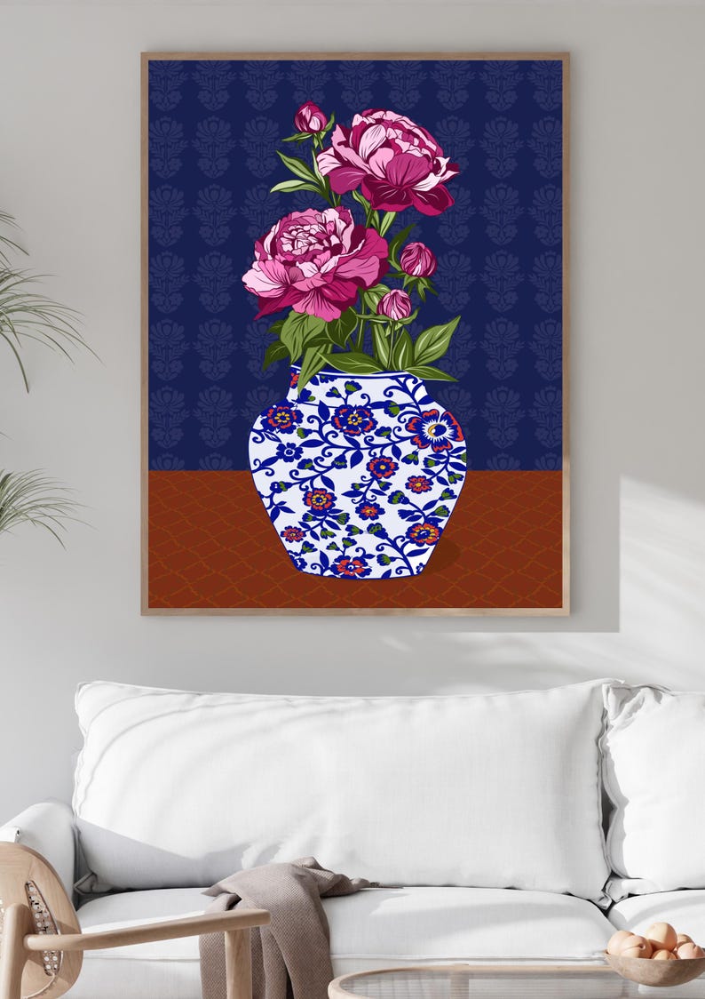 May include: A framed wall art print featuring a white ceramic vase with blue and orange floral patterns. The vase holds several vibrant magenta peony flowers and green leaves. The background is a deep navy blue with a subtle repeating pattern.