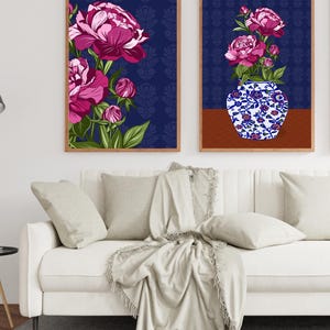 May include: Two framed wall art prints featuring vibrant magenta peonies against a dark blue patterned background. One print displays a cluster of flowers, while the other shows peonies in a blue and white floral patterned vase on a brown surface.