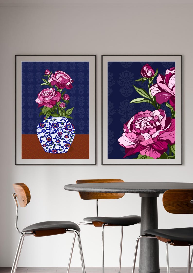 May include: Two framed wall art prints featuring vibrant pink peony flowers. The left print displays a blue and white floral vase with peonies on a brown surface. The right print shows a close-up of large pink peony blossoms against a dark blue background.