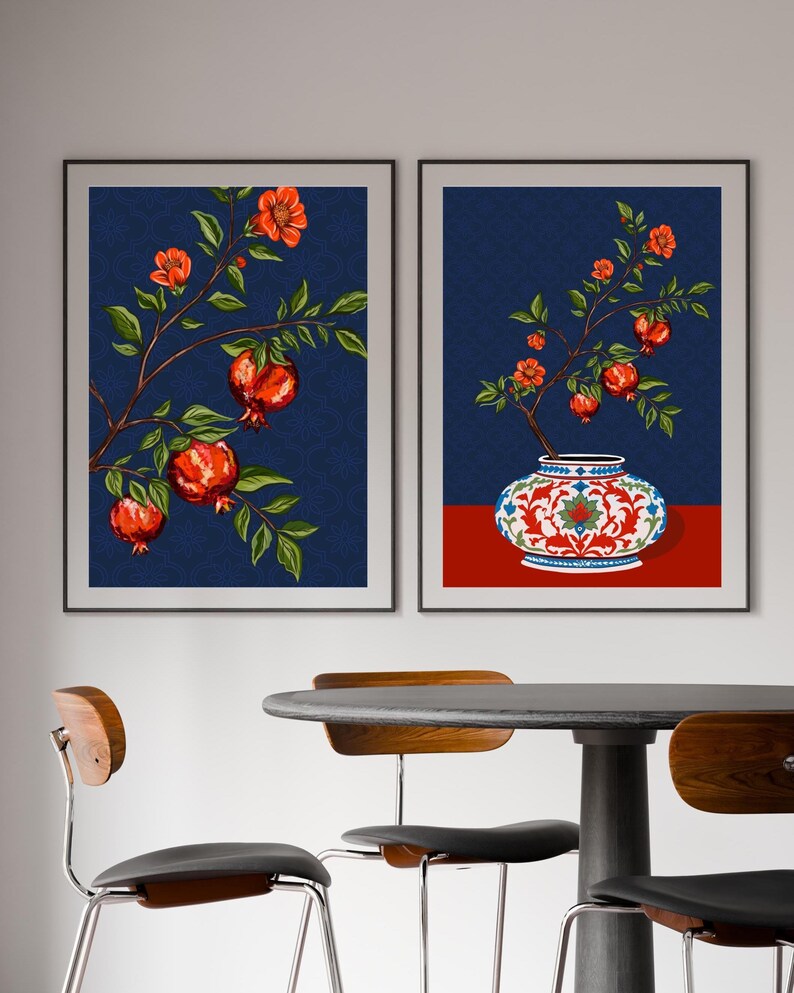 May include: Two framed wall art prints featuring pomegranate branches with red fruit and green leaves against a dark blue patterned background. One print shows a branch, while the other depicts a branch emerging from a decorative white and red vase.