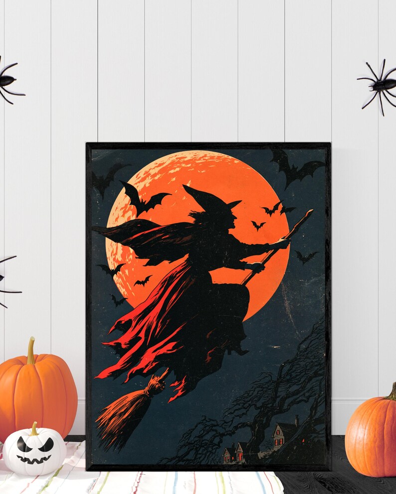 K&ouml;nnte beinhalten: Ein gerahmter, rechteckiger Kunstdruck f&uuml;r die Wand mit der schwarzen Silhouette einer Hexe, die auf einem Besen vor einem gro&szlig;en, leuchtend orangefarbenen Vollmond fliegt. Der dunkle Nachthimmel ist voller Flederm&auml;use und ein Dorf.