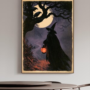 Peut inclure: Une impression d'art mural rectangulaire repr&eacute;sentant une sc&egrave;ne sombre et atmosph&eacute;rique d'une silhouette v&ecirc;tue d'une cape noire et d'un chapeau pointu marchant sur un chemin la nuit. La silhouette porte une lanterne orange. Lune, corbeaux et chauves-souris.