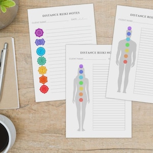 May include: A collection of Distance Reiki Notes on a wooden surface. The notes feature chakra illustrations and lined spaces for client information and notes. A pen, notebook, and coffee cup are also present.