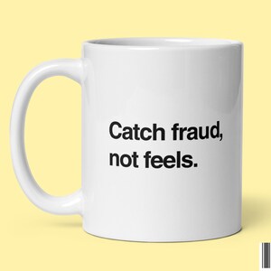 Könnte beinhalten: Weiße Keramik-Kaffeetasse mit schwarzem Text, der "Catch fraud, not feels." lautet.