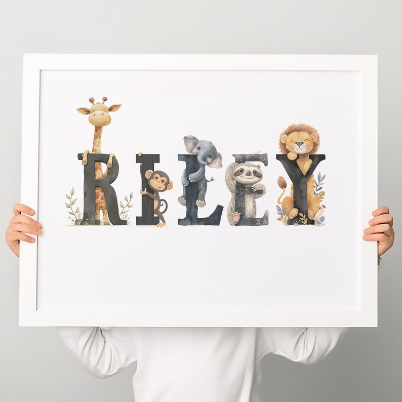 K&ouml;nnte beinhalten: Ein wei&szlig;er gerahmter Druck mit dem Namen "RILEY", der in schwarzen Buchstaben geschrieben ist. Jeder Buchstabe ist mit einem anderen Tier verziert, darunter eine Giraffe, ein Affe, ein Elefant, ein Faultier und ein L&ouml;we.