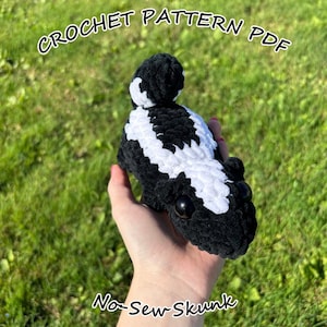 May include: Crochet pattern PDF for a no-sew skunk amigurumi. The skunk is black and white with a fluffy tail and black eyes.
