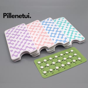 Puede incluir: La imagen muestra un blíster verde de pastillas anticonceptivas junto a cuatro estuches blancos con patrones abstractos coloridos. Los estuches son de color morado, rosa, azul y turquesa. El texto "Pillenetui." es visible.