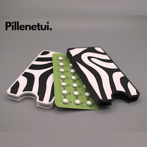 Könnte beinhalten: Drei Pillendosen mit einem schwarz-weißen Zebra-Muster. Die Dosen sind aus hartem Kunststoff und haben einen Schlitz zum Aufbewahren einer Pillenpackung. Die Pillenpackung ist grün und enthält weiße Pillen.