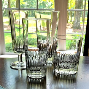 Puede incluir: Cuatro vasos de vidrio transparente para beber con un diseño texturizado. Los vasos están sobre una mesa de madera oscura.