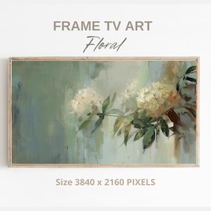 May include: A framed floral art print for a TV screen. The artwork features a soft, impressionistic painting of white flowers and green leaves against a muted green and blue background. The text "FRAME TV ART" and "Floral" are at the top.