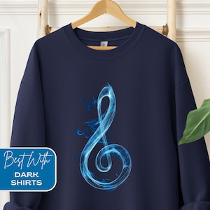 May include: Navy blue sweatshirt featuring a stylized blue treble clef design. The graphic has a smoky, ethereal appearance. The lower left corner of the sweatshirt has a white box with the text "Best With" and "Dark Shirts".