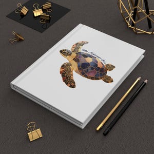 May include: White notebook with a watercolor illustration of a sea turtle with a galaxy-like shell. The text "My Hawaiian Sea" is printed on the cover.