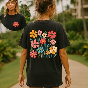 May include: Black t-shirt with a colorful floral design on the back and a smaller flower on the front. The flowers are in shades of pink, yellow, blue, and red. The shirt is a casual style.