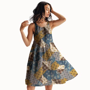 May include: A sleeveless A-line dress featuring a patchwork design with alternating squares of muted blue, mustard yellow, and cream. The pattern includes various geometric shapes, floral motifs, and linear elements across the entire garment.