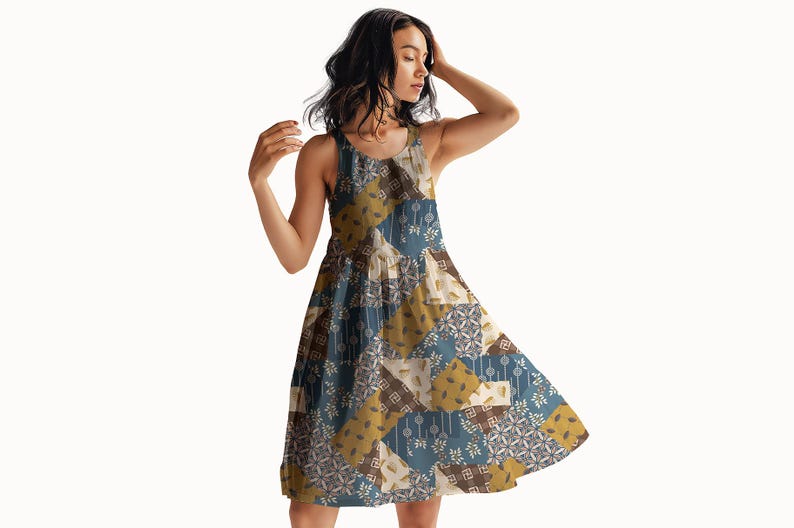 May include: A sleeveless A-line dress featuring a patchwork design with alternating squares of muted blue, mustard yellow, and cream. The pattern includes various geometric shapes, floral motifs, and linear elements across the entire garment.