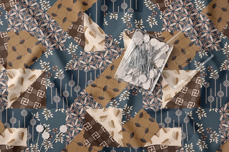 May include: A fabric featuring a patchwork design in shades of blue, brown, and cream with various floral and geometric patterns. A clear plastic container filled with white-headed sewing pins rests on the fabric, with two loose pins nearby.