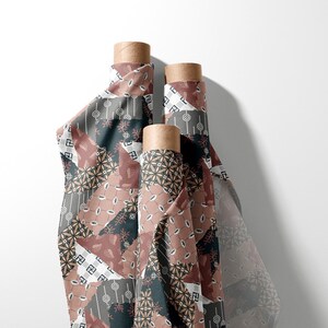 May include: Three vertical rolls of fabric featuring a patchwork design in shades of dusty rose, dark charcoal, and white. The pattern consists of various geometric shapes, floral motifs, and small repeating symbols printed across the textile surface.
