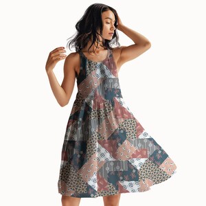 May include: A sleeveless knee-length dress featuring a patchwork design with various geometric and floral patterns in shades of dusty rose, slate blue, white, and charcoal gray. The garment has a round neckline and a flared, A-line silhouette.