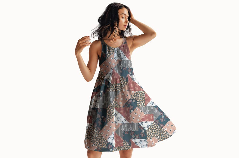 May include: A sleeveless knee-length dress featuring a patchwork design with various geometric and floral patterns in shades of dusty rose, slate blue, white, and charcoal gray. The garment has a round neckline and a flared, A-line silhouette.