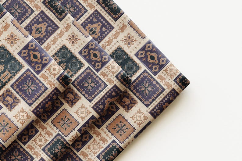 May include: Folded fabric featuring a repeating pattern of geometric shapes, including squares and diamonds, in shades of blue, brown, and beige. The design incorporates elephant and floral motifs, creating a textured, decorative appearance. The fabric is folded over on a white surface.