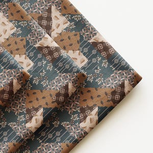 May include: A folded piece of fabric featuring a patchwork design in shades of dark teal, brown, and cream. The pattern consists of repeating geometric shapes, including small squares with swastika-like symbols, leaf motifs, and dotted lines.