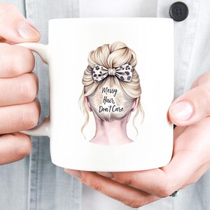 K&ouml;nnte beinhalten: Wei&szlig;er Keramikbecher mit einer Illustration einer Hochsteckfrisur einer Frau und einer Schleife mit Leopardenmuster. Der Text "Messy Hair, Don't Care" ist auf dem Becher aufgedruckt. Der Becher wird von einer Person gehalten.