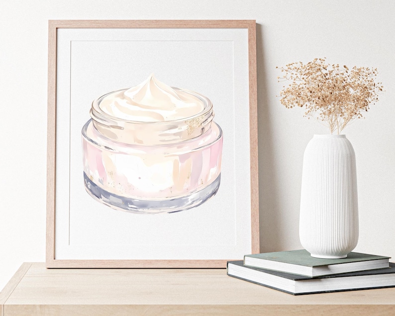 May include: Watercolor illustration of a jar of cream with a light pink and gold design. The jar is displayed in a wooden frame, with a white vase and books in the background.
