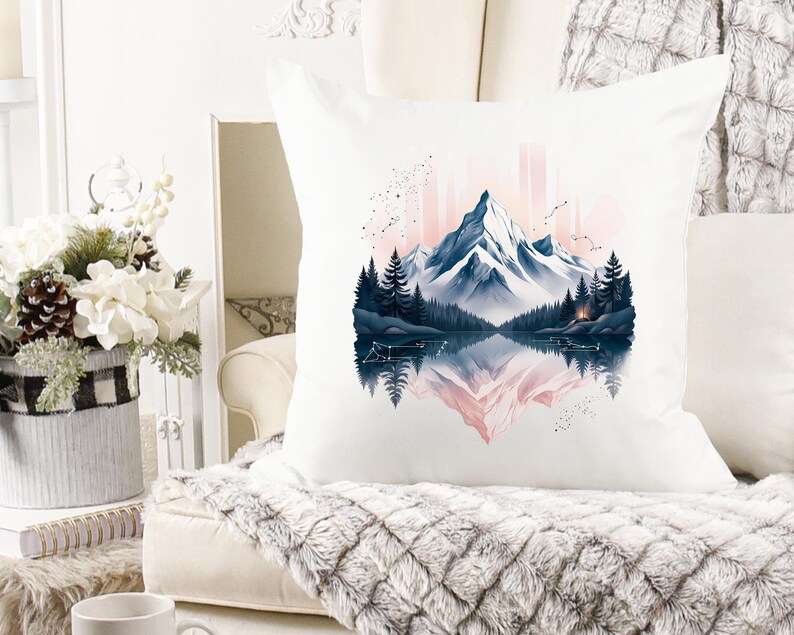 Pode incluir: Almofada quadrada branca com uma paisagem de montanha em aquarela com um lago e &aacute;rvores. O design inclui uma cordilheira em tons de azul e rosa, com um reflexo espelhado na &aacute;gua.