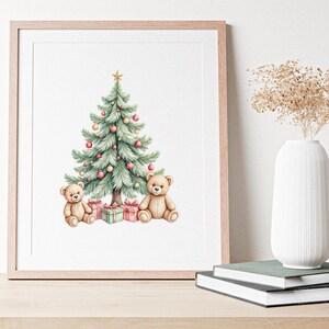 Puede incluir: Impresi&oacute;n en acuarela enmarcada de un &aacute;rbol de Navidad adornado con adornos y una estrella dorada, flanqueado por dos osos de peluche y regalos. La obra de arte est&aacute; en un marco de madera clara, expuesta sobre una superficie de madera.