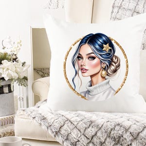 Pode incluir: Almofada decorativa branca com uma ilustra&ccedil;&atilde;o digital de uma mulher com cabelo azul e loiro, um acess&oacute;rio de cabelo de estrela dourada e brincos dourados. O retrato est&aacute; dentro de um c&iacute;rculo de glitter dourado.